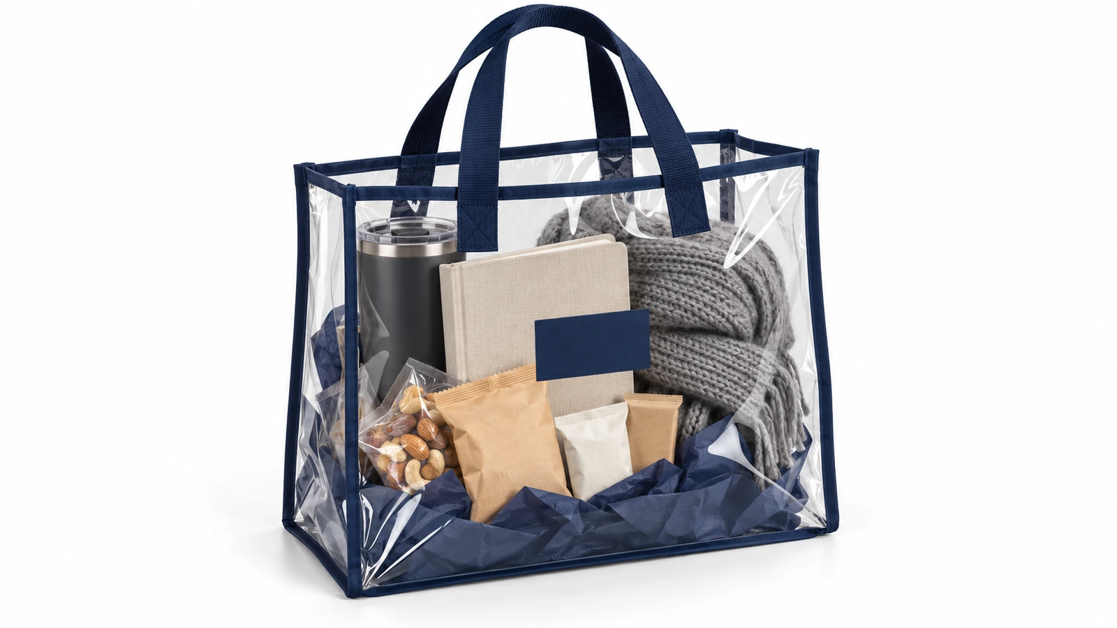 Clear PVC tote with navy binding holding a curated corporate gift kit of a tumbler, notebook, snacks and a folded scarf, all visible through the bag
