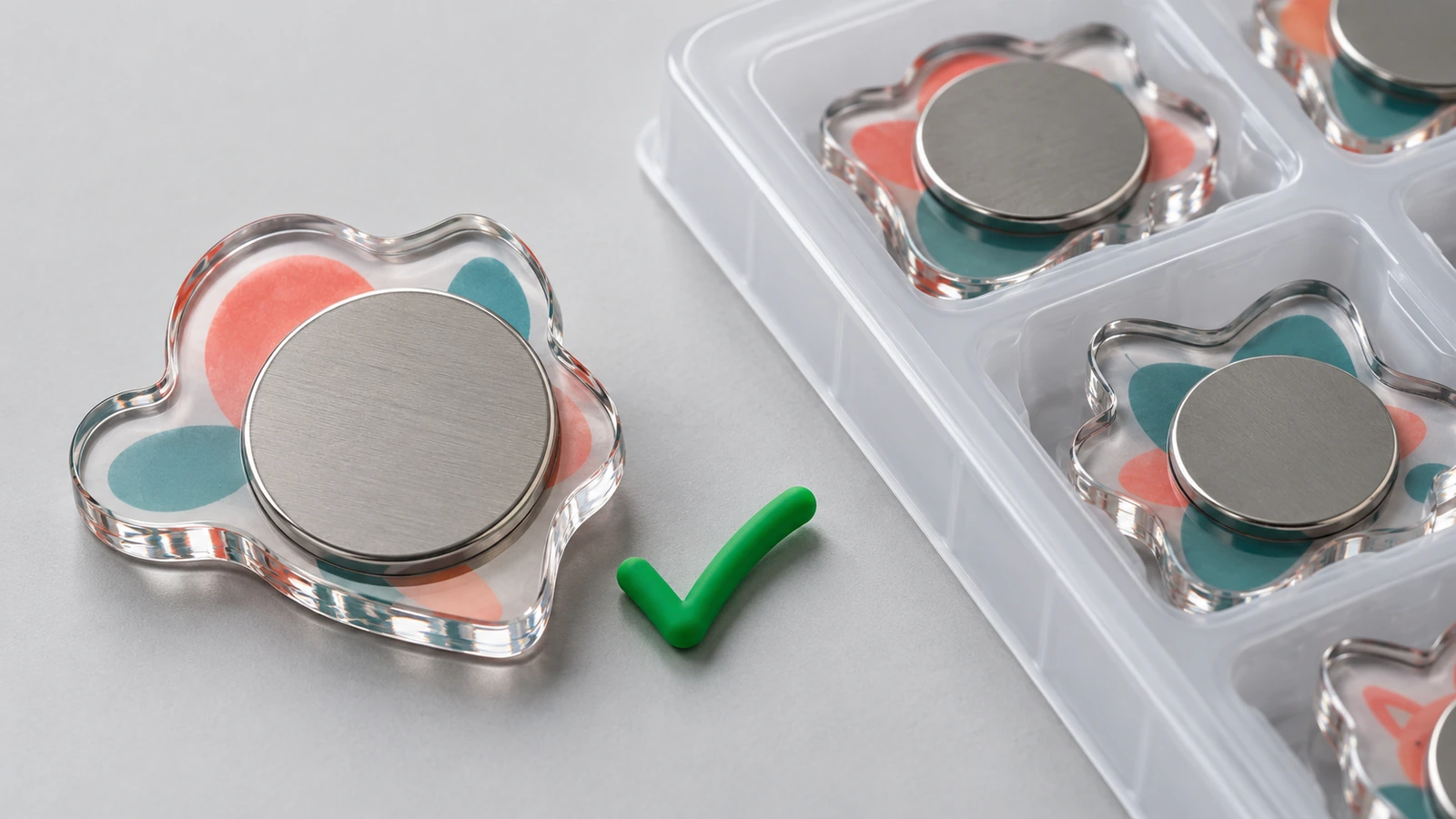 Close-up of the back of a clear acrylic magnet showing a magnet disc fully bonded flush to the surface beside a protective tray