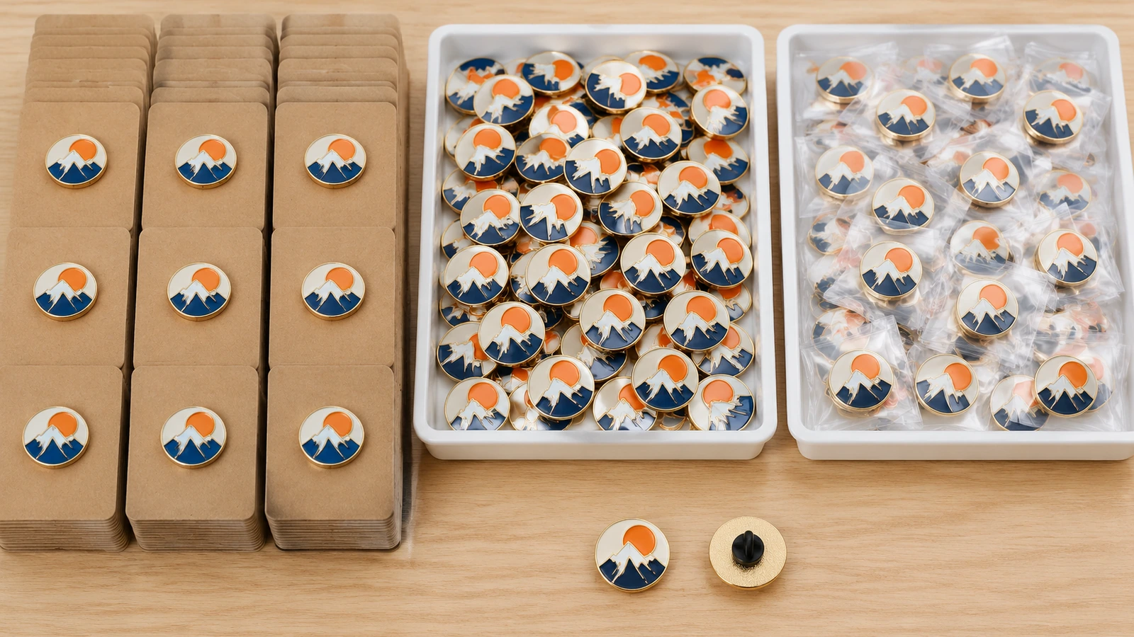 Overhead view of soft enamel pins on blank backing cards sorted into neat stacks and trays for event distribution