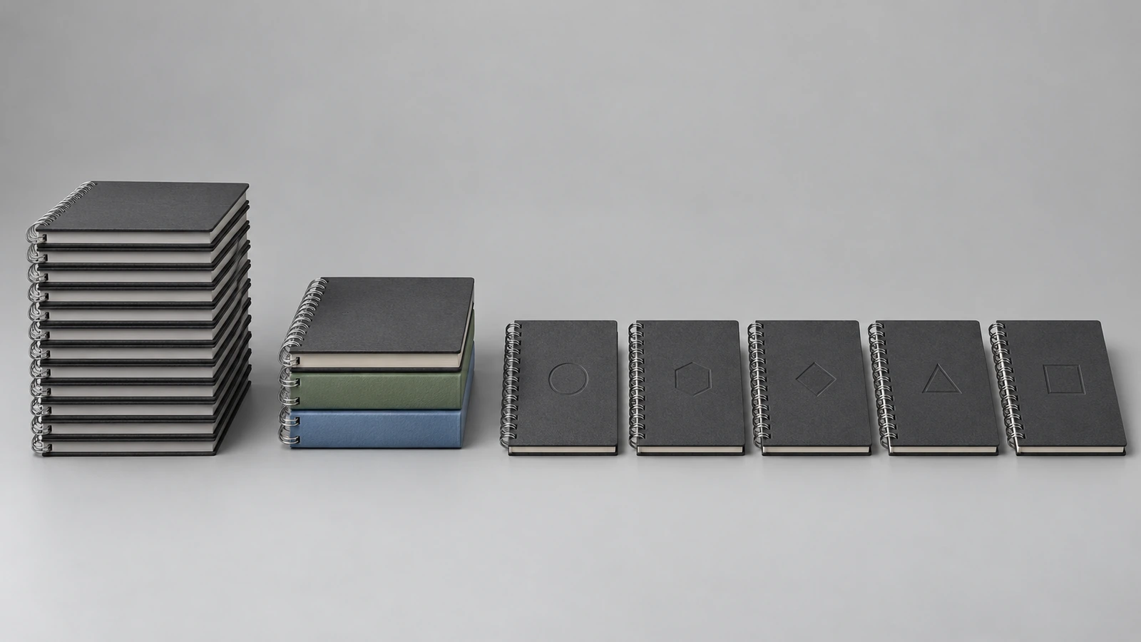 Three groups of wire-bound notebooks showing increasing customization: one identical stack, a stack split into three cover colors, and a row of notebooks each marked with a different small emblem